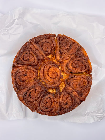 Loafology Bakery & Café’s Cinnamon Scrolls—round, golden-brown pastries with spiral segments—are presented on crumpled white parchment paper against a white background.