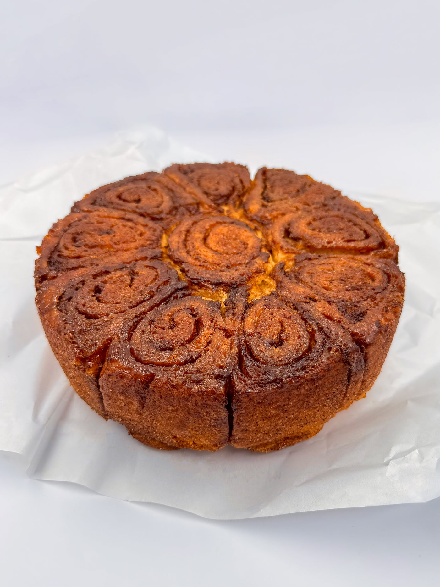 Cinnamon Scrolls by Loafology Bakery & Café, sliced into sections, rest on white parchment paper against a plain background.