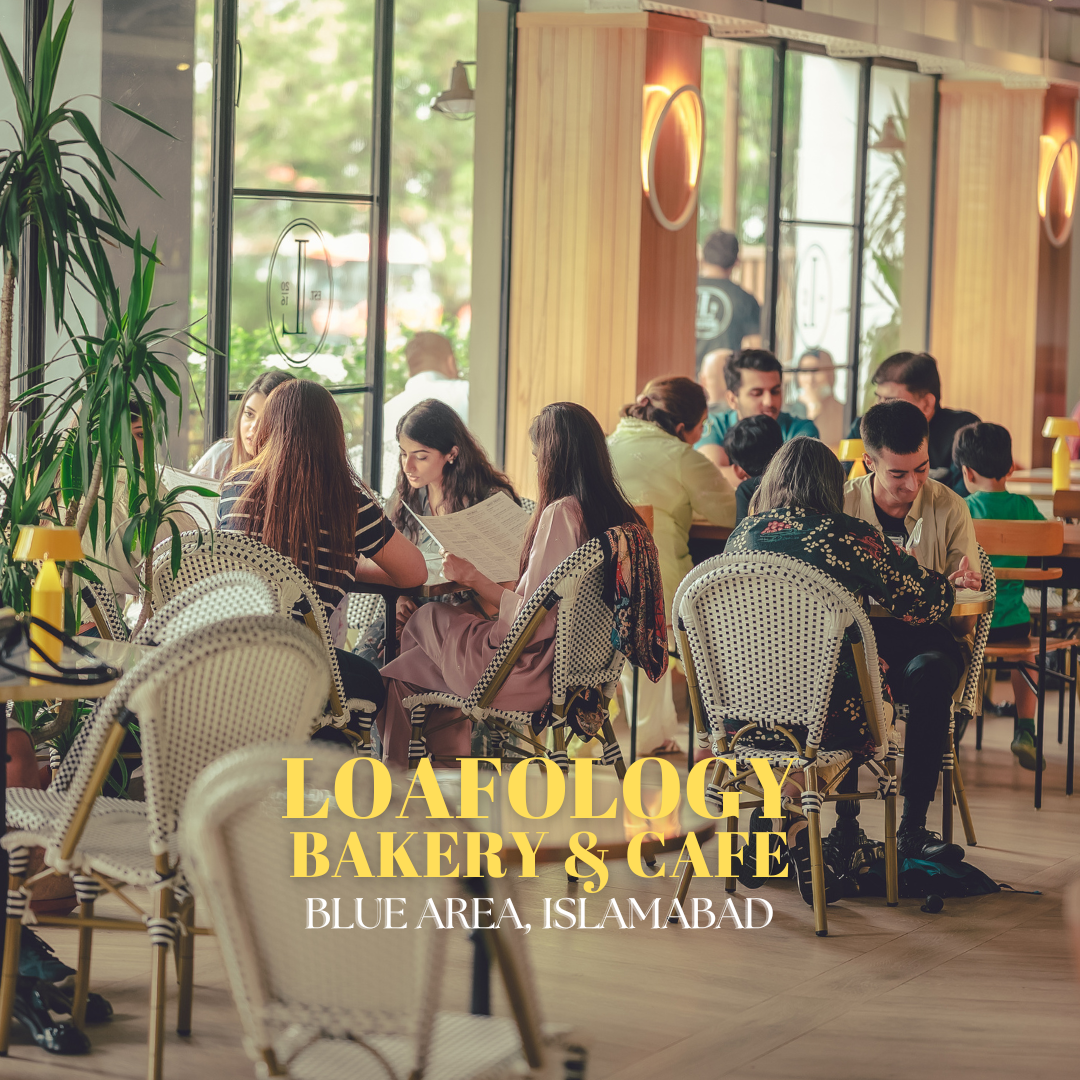 Customers dine and converse inside Loafology Bakery & Café in Blue Area, Islamabad. The interior is brightly lit with large windows and has wicker chairs and tables.