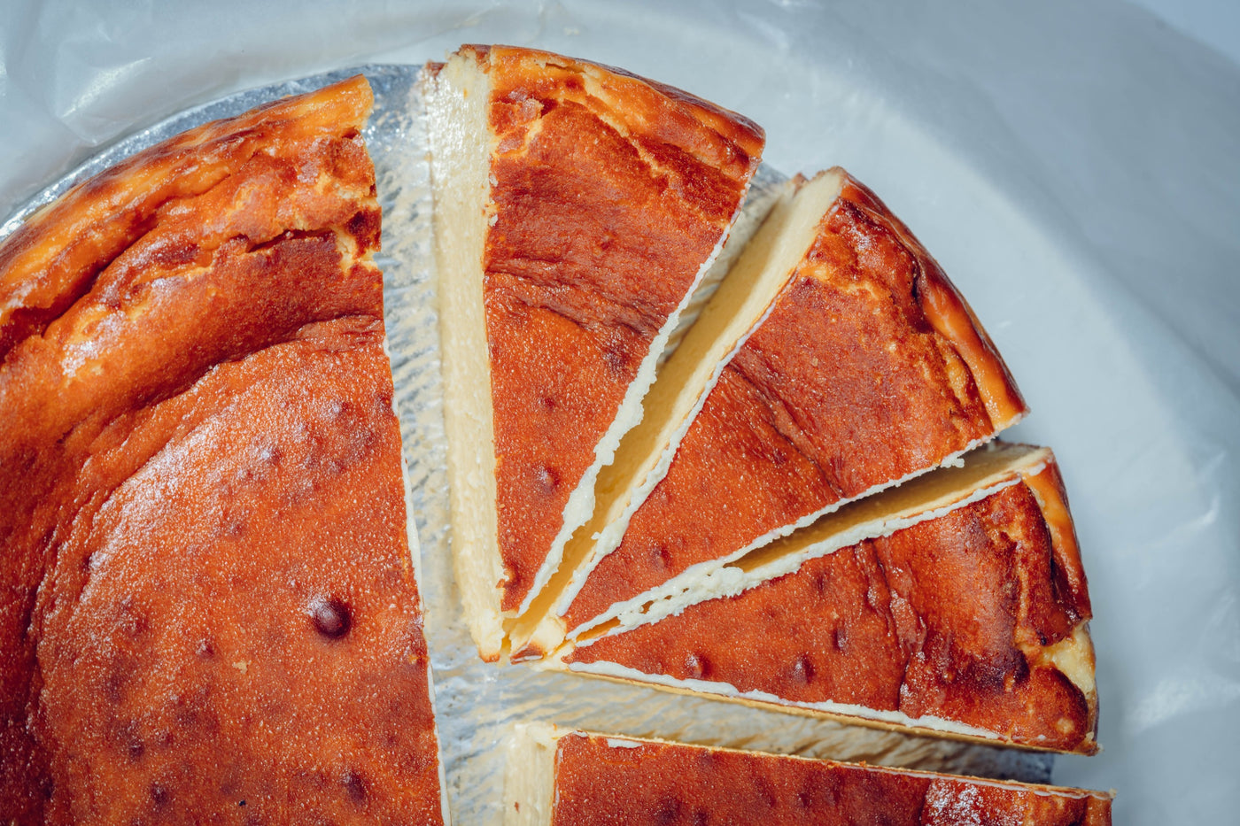 A top view of Loafology Bakery & Café's San Sebastián Cheese Cake showcases five slightly separated slices, revealing its rich and creamy texture with a golden-brown crust.